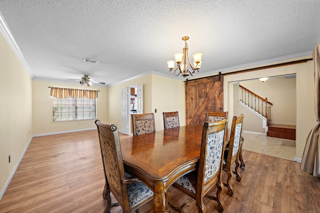 dining area featuring a barn door, light hardwood / wood-style floors, and a textured ceiling