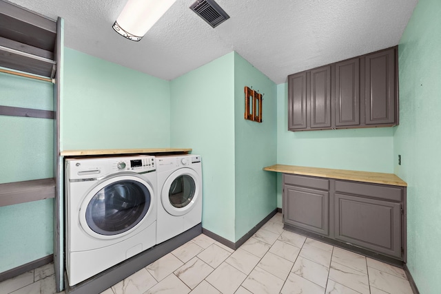 washroom with cabinets, a textured ceiling, and independent washer and dryer