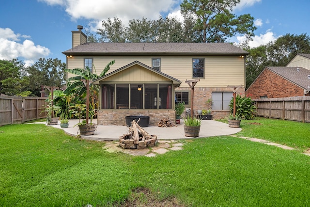 rear view of house featuring a lawn, an outdoor fire pit, a patio area, and a sunroom