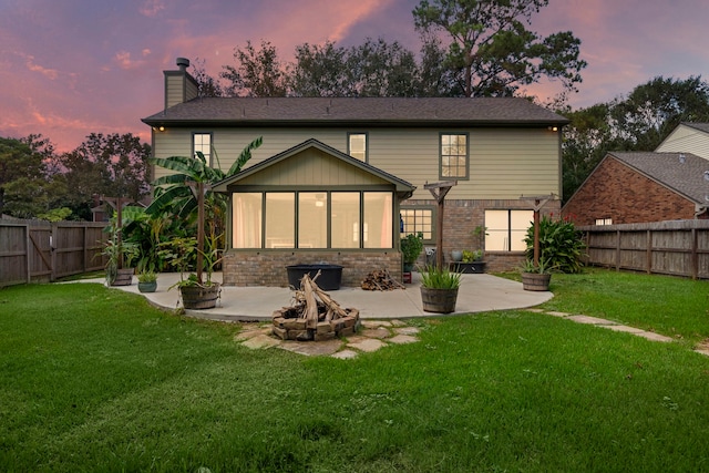 back house at dusk with a patio area, a yard, and an outdoor fire pit