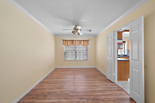 empty room with a textured ceiling, hardwood / wood-style flooring, ceiling fan, and crown molding