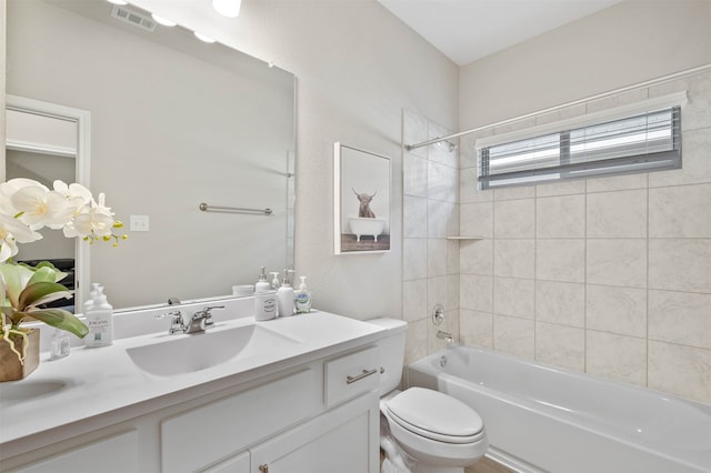 full bathroom featuring vanity, tiled shower / bath combo, and toilet