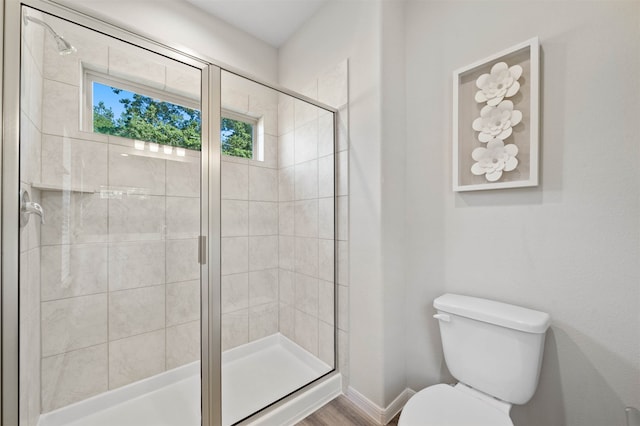 bathroom featuring hardwood / wood-style floors, toilet, and a shower with shower door