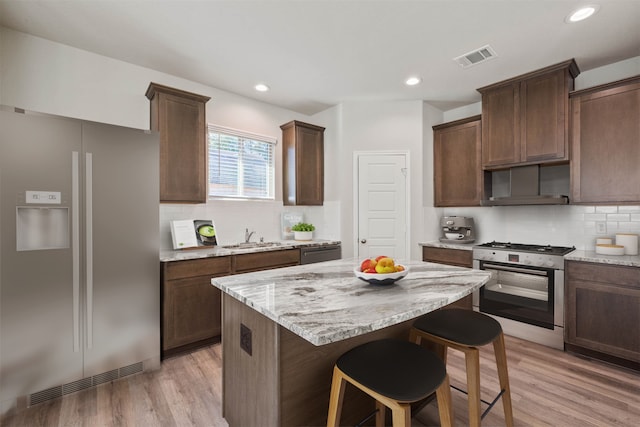 kitchen featuring dark brown cabinets, stainless steel appliances, and light hardwood / wood-style floors