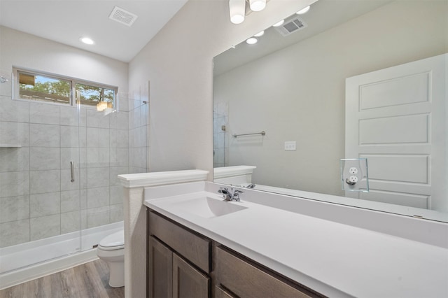 bathroom with vanity, a shower with shower door, toilet, and hardwood / wood-style flooring