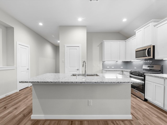 kitchen featuring light wood-type flooring, a kitchen island with sink, sink, decorative backsplash, and stainless steel appliances