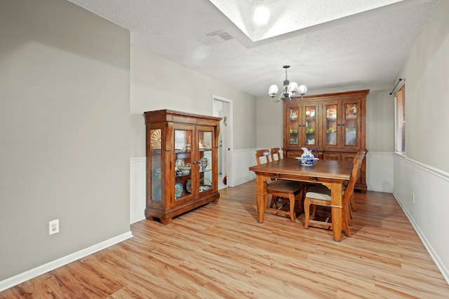 dining space featuring a notable chandelier, light hardwood / wood-style floors, and a textured ceiling