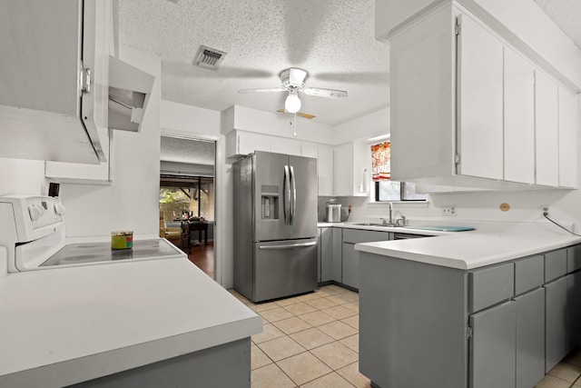 kitchen featuring stainless steel fridge, gray cabinetry, and a wealth of natural light