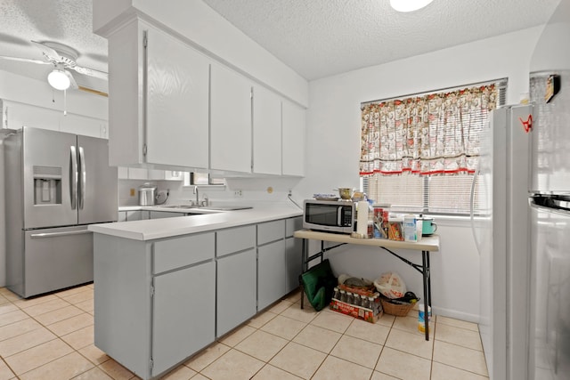 kitchen with a textured ceiling, light tile patterned flooring, ceiling fan, and stainless steel appliances