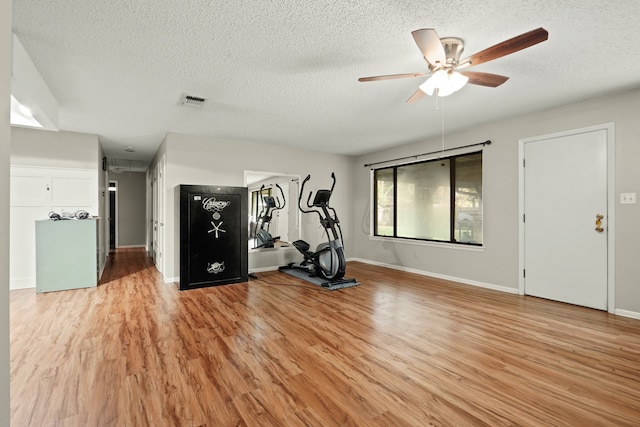 exercise area featuring a textured ceiling, ceiling fan, and light hardwood / wood-style flooring