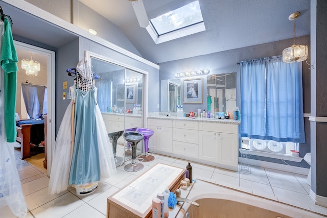 bathroom featuring vanity, tile patterned floors, lofted ceiling with skylight, and a bathing tub