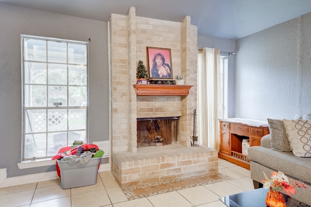 living room featuring a brick fireplace and light tile patterned floors