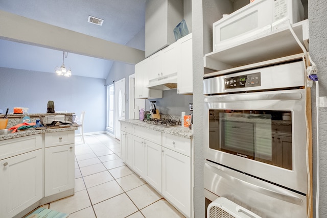 kitchen with appliances with stainless steel finishes, vaulted ceiling, light stone countertops, and white cabinetry