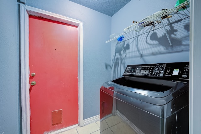 laundry area with washer / dryer, a textured ceiling, and light tile patterned flooring