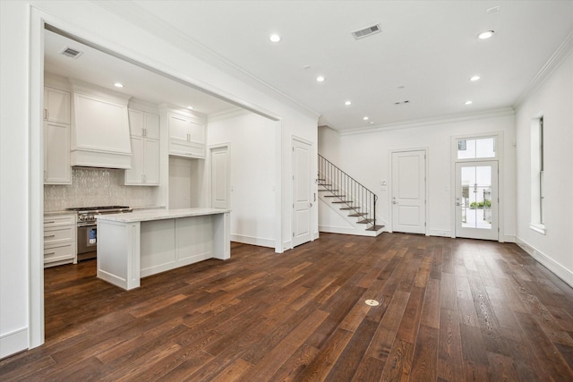 kitchen with high end stainless steel range, crown molding, dark wood-style floors, tasteful backsplash, and white cabinets