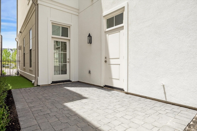 entrance to property featuring stucco siding, a patio area, and fence