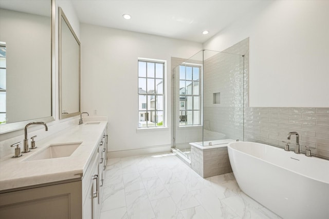 full bathroom featuring a freestanding tub, marble look tiles, a shower stall, double vanity, and recessed lighting