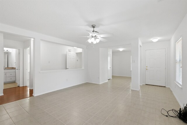 unfurnished living room featuring ceiling fan and light tile patterned floors