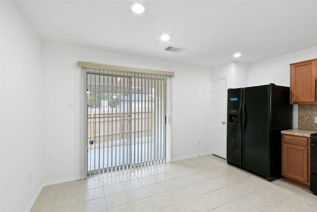 kitchen featuring backsplash, light tile patterned floors, and black appliances