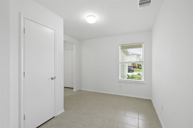 unfurnished room featuring a textured ceiling and light tile patterned flooring