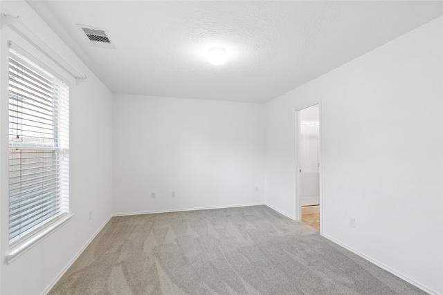 unfurnished room featuring a textured ceiling and light carpet