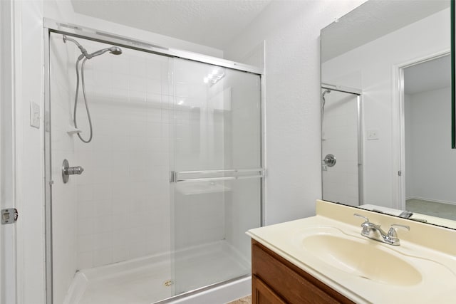 bathroom with vanity, a textured ceiling, and a shower with door