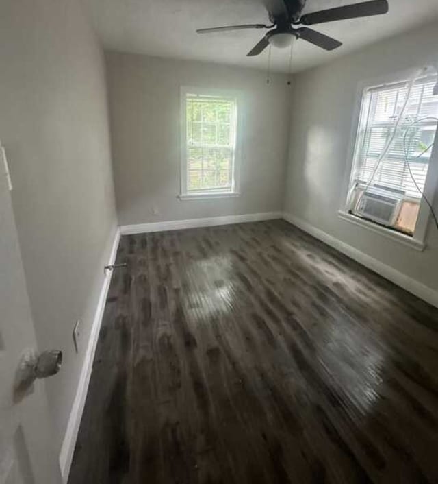 spare room with plenty of natural light, dark wood-type flooring, and ceiling fan