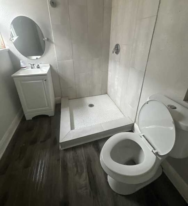 bathroom featuring vanity, wood-type flooring, toilet, and a shower