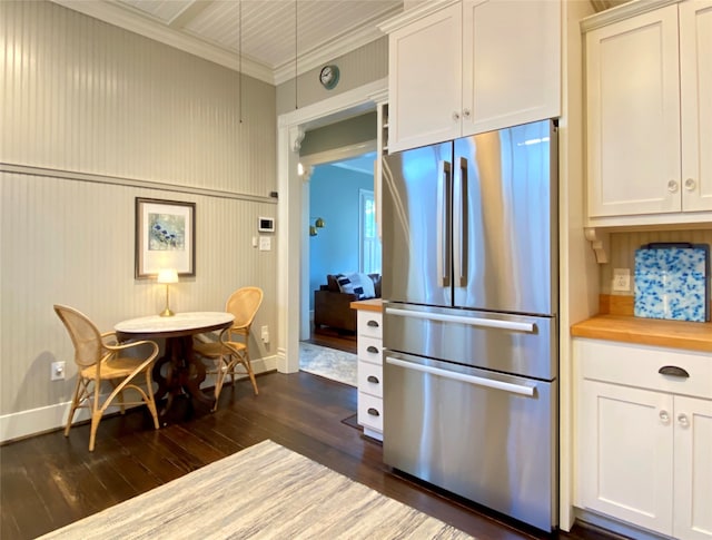 kitchen with white cabinets, dark wood-type flooring, stainless steel fridge, and ornamental molding