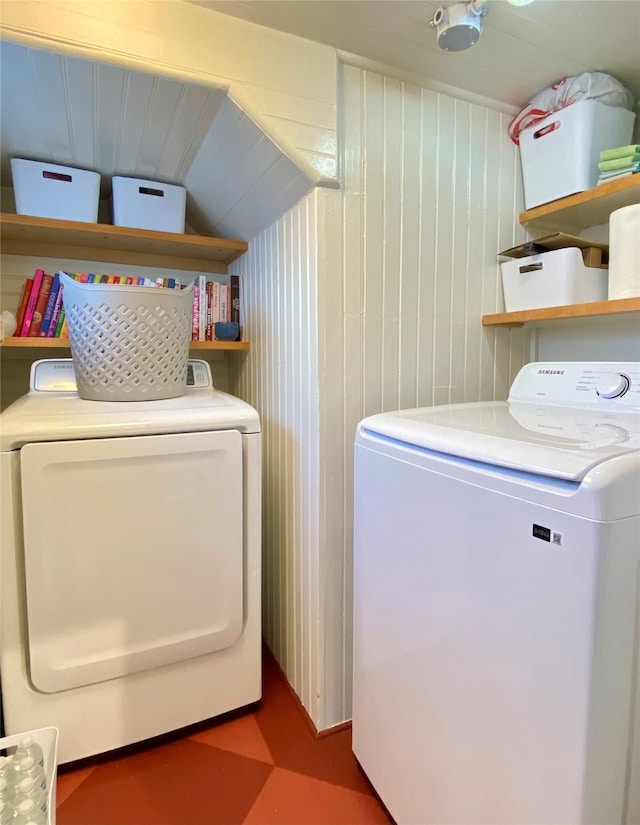 clothes washing area with wood walls and washer and dryer