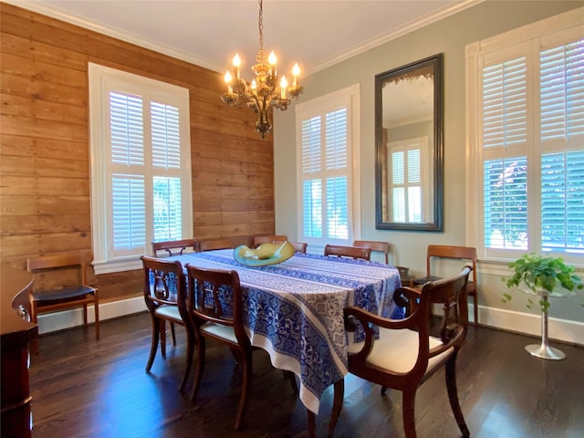 dining space with crown molding, wood finished floors, wood walls, baseboards, and a notable chandelier