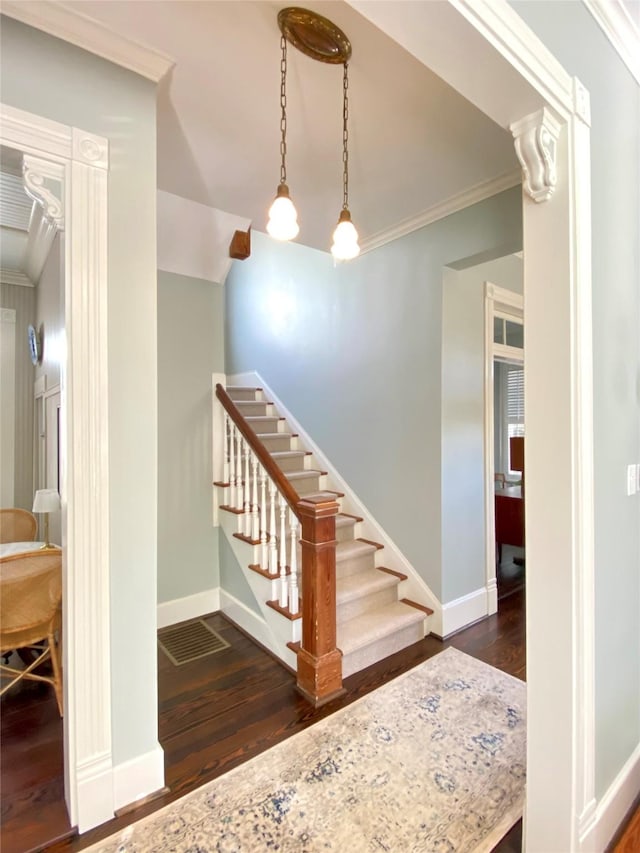 stairs featuring baseboards, ornamental molding, and wood finished floors