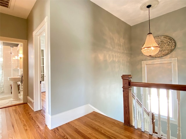 interior space with visible vents, baseboards, a chandelier, and wood finished floors