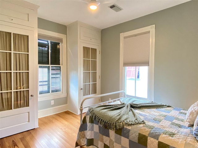 bedroom featuring visible vents, multiple windows, baseboards, and light wood-style flooring