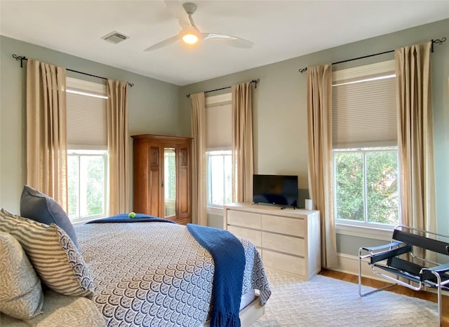 bedroom featuring wood finished floors, baseboards, a ceiling fan, and visible vents