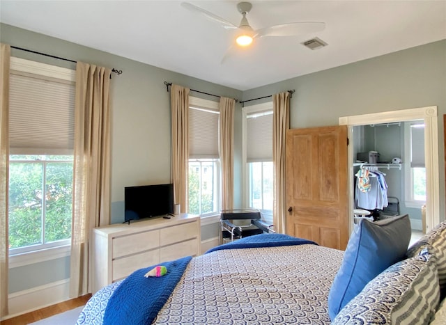 bedroom featuring visible vents, ceiling fan, multiple windows, and wood finished floors