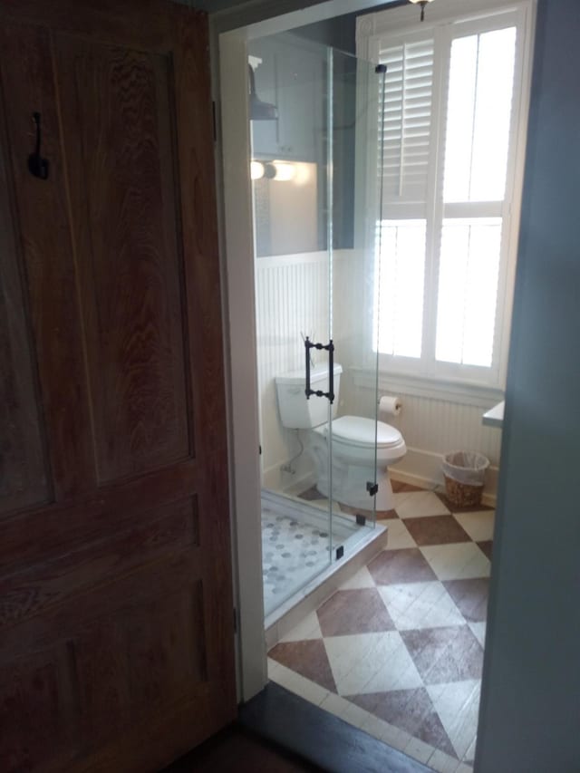 full bath with toilet, tile patterned floors, and a shower stall