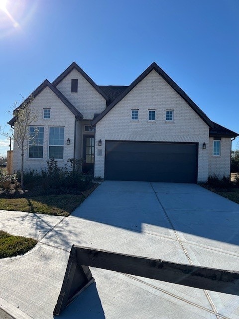 view of front of property featuring a garage, concrete driveway, and brick siding