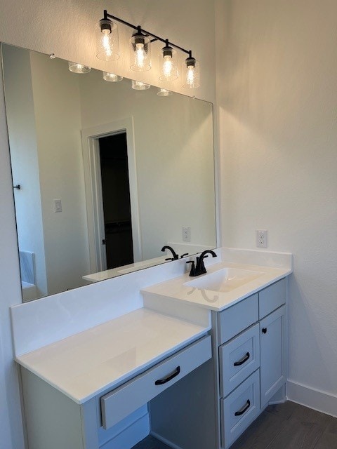 bathroom with wood finished floors, vanity, and baseboards