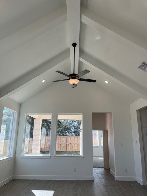 spare room featuring lofted ceiling with beams, dark hardwood / wood-style floors, and ceiling fan