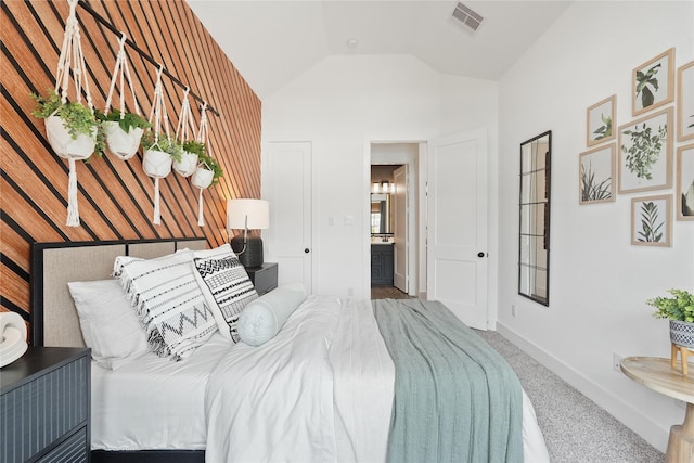 carpeted bedroom featuring lofted ceiling, visible vents, baseboards, and ensuite bathroom