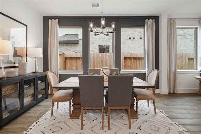 dining room featuring visible vents, a notable chandelier, baseboards, and wood finished floors