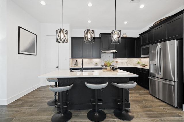 kitchen featuring appliances with stainless steel finishes, dark cabinets, and decorative light fixtures