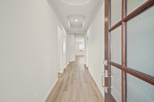 hallway with hardwood / wood-style flooring and a raised ceiling