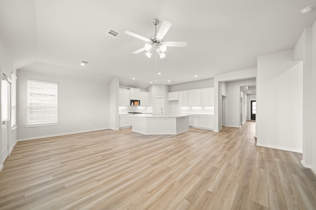 unfurnished living room featuring ceiling fan, sink, and light wood-type flooring