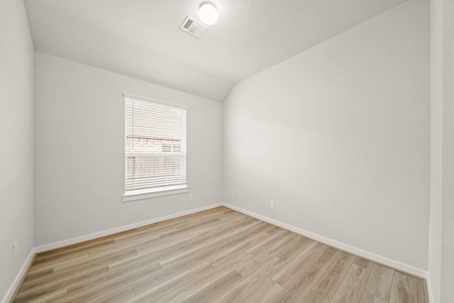 unfurnished room with light wood-type flooring and vaulted ceiling