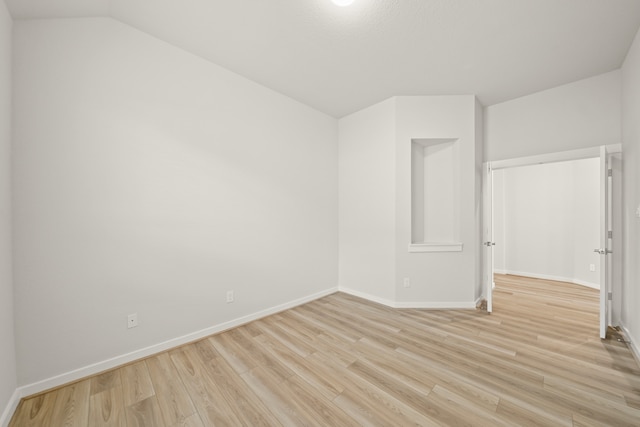 empty room featuring vaulted ceiling and light wood-type flooring