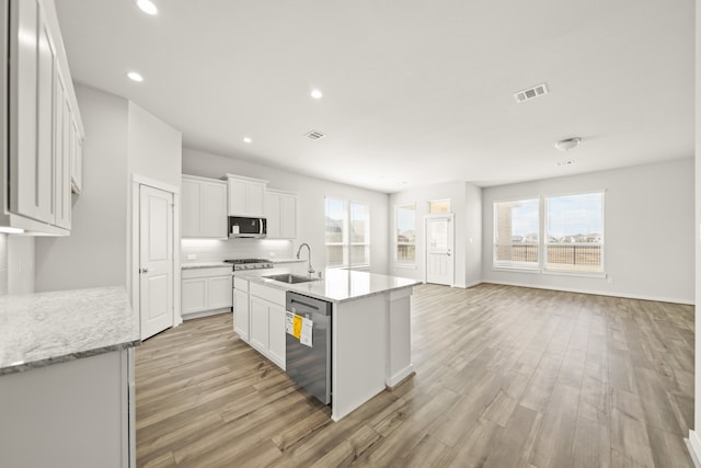 kitchen with a kitchen island with sink, light hardwood / wood-style flooring, stainless steel appliances, sink, and white cabinets