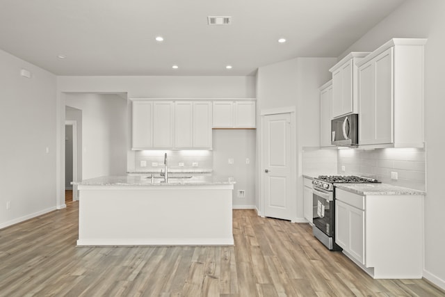 kitchen featuring sink, stainless steel appliances, white cabinets, light hardwood / wood-style flooring, and a kitchen island with sink