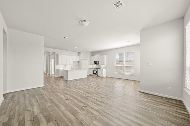 unfurnished living room featuring light hardwood / wood-style flooring and sink